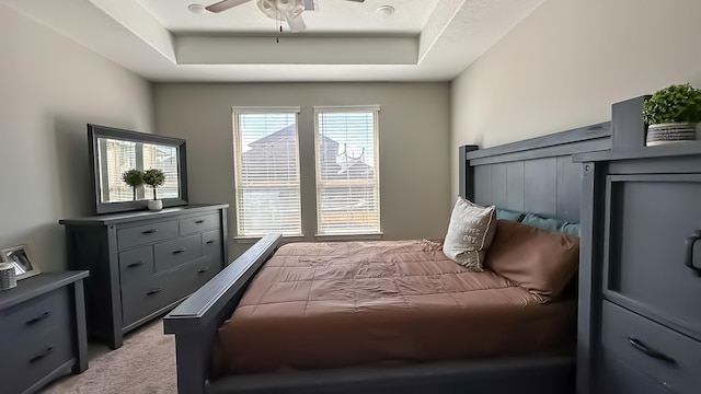 bedroom featuring light carpet, a raised ceiling, and ceiling fan