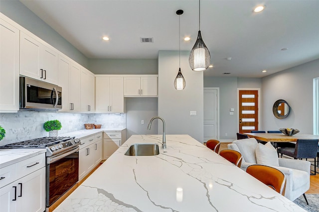 kitchen featuring white cabinetry, stainless steel appliances, sink, and light stone counters