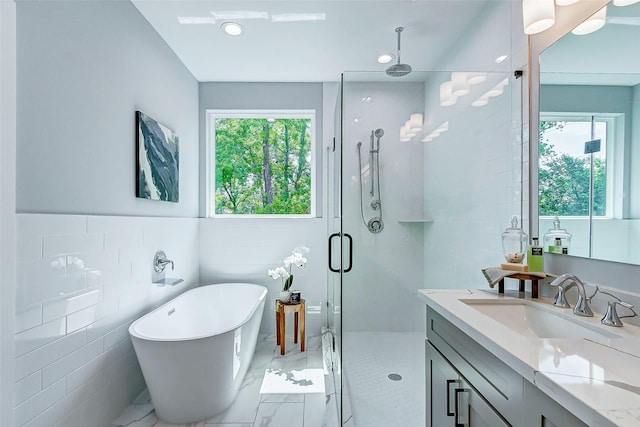 bathroom featuring tile walls, vanity, and separate shower and tub