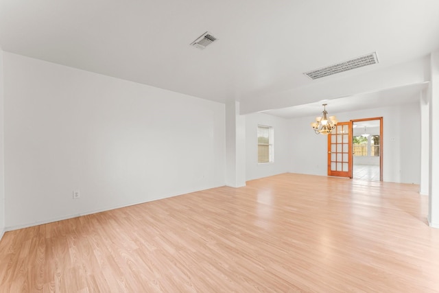 spare room featuring light hardwood / wood-style flooring and a chandelier