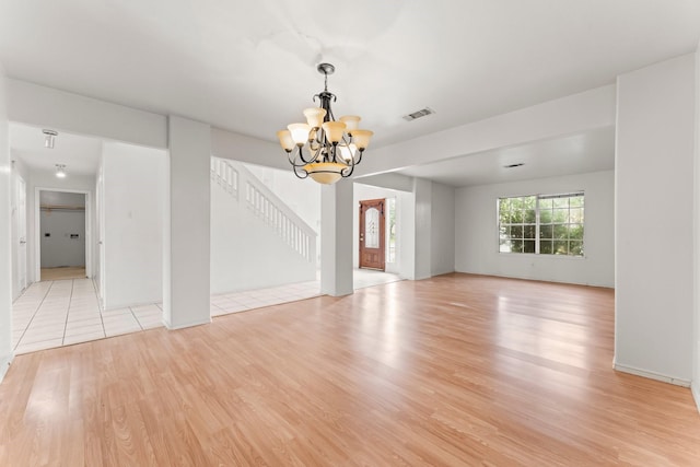 empty room featuring a chandelier and light wood-type flooring