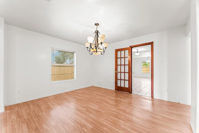 unfurnished room featuring an inviting chandelier and light hardwood / wood-style floors