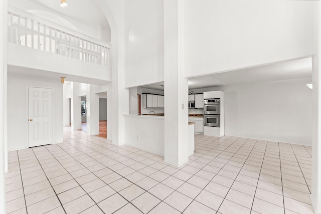 unfurnished living room featuring light tile patterned floors and a high ceiling