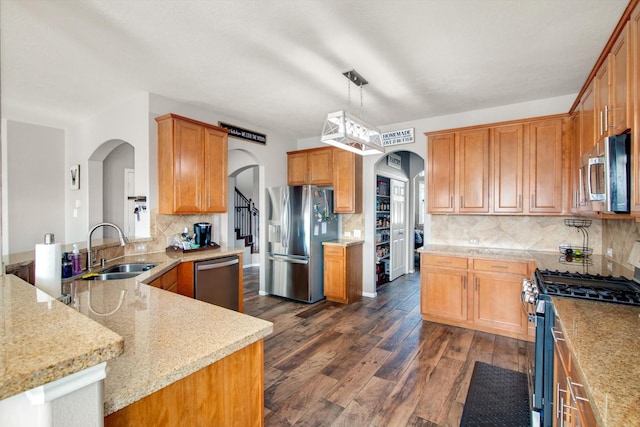 kitchen with sink, appliances with stainless steel finishes, dark hardwood / wood-style floors, light stone countertops, and decorative light fixtures