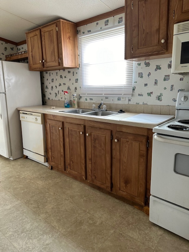 kitchen featuring crown molding, white appliances, sink, and backsplash