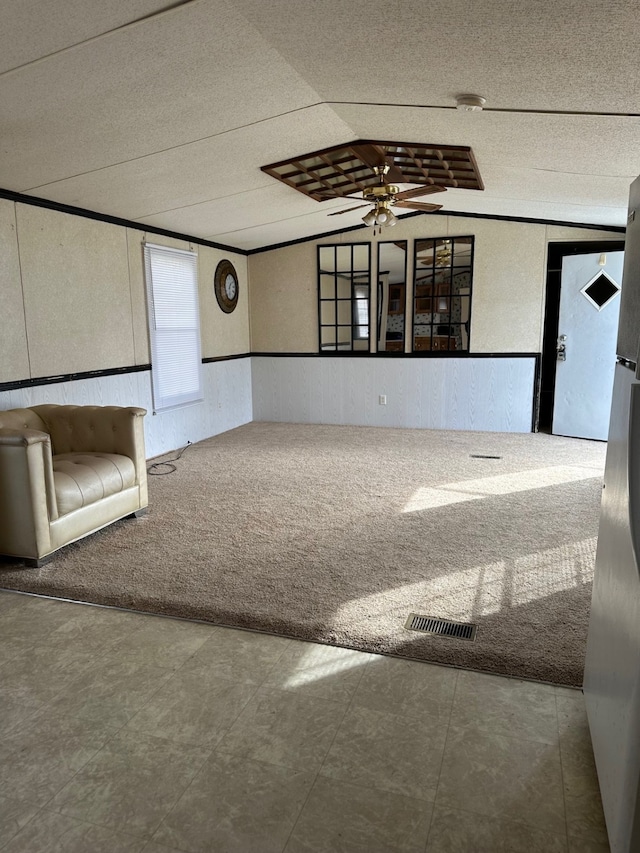 unfurnished living room featuring ornamental molding, carpet, lofted ceiling, and ceiling fan