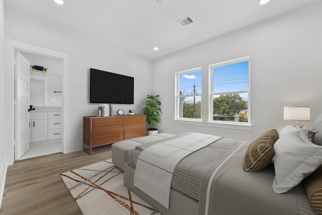 bedroom with ensuite bathroom and light wood-type flooring