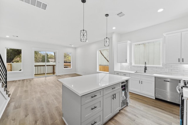 kitchen featuring pendant lighting, sink, dishwasher, a kitchen island, and decorative backsplash