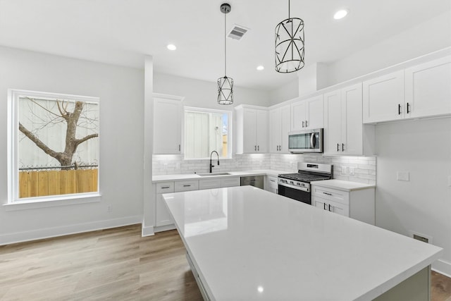 kitchen featuring white cabinetry, hanging light fixtures, a center island, and appliances with stainless steel finishes