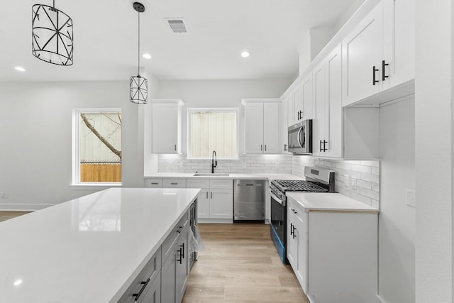 kitchen featuring white cabinetry, stainless steel appliances, decorative light fixtures, and sink