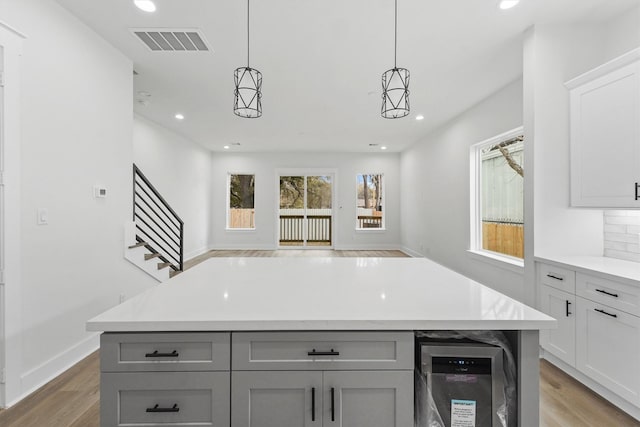 kitchen with pendant lighting, gray cabinets, tasteful backsplash, wood-type flooring, and a kitchen island