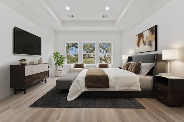 bedroom featuring a raised ceiling and light hardwood / wood-style floors