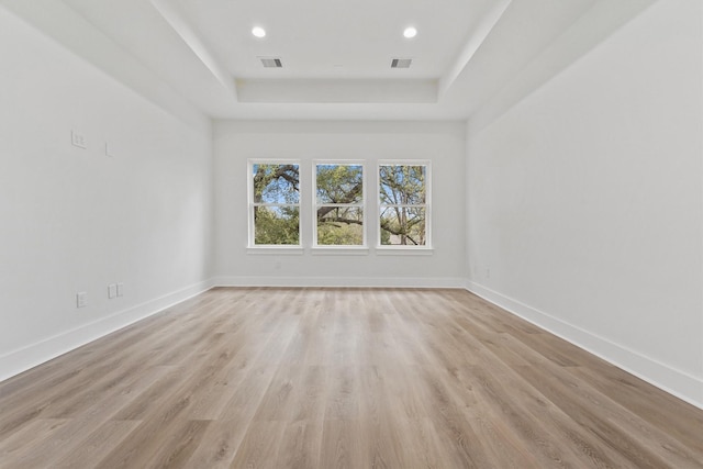 unfurnished room featuring light hardwood / wood-style flooring and a raised ceiling