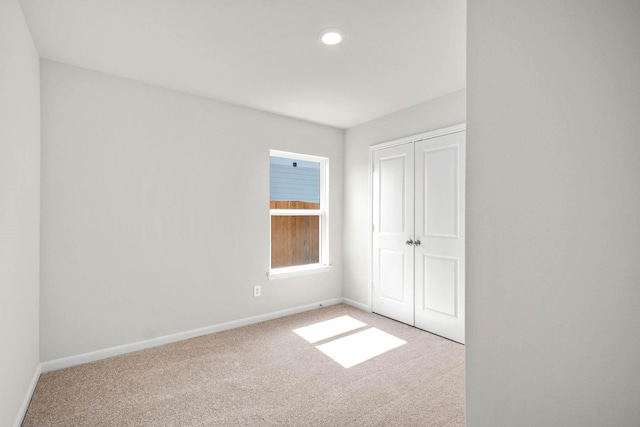 unfurnished bedroom featuring light colored carpet and a closet