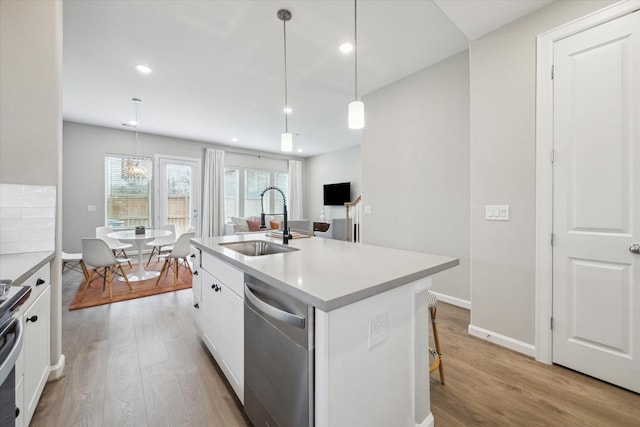 kitchen featuring sink, white cabinetry, stainless steel dishwasher, an island with sink, and pendant lighting