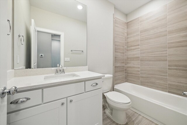 full bathroom featuring vanity, tiled shower / bath, and toilet