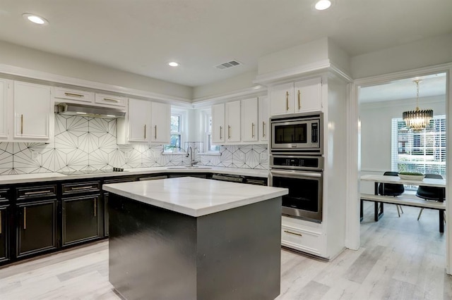 kitchen with white cabinetry, tasteful backsplash, a center island, hanging light fixtures, and appliances with stainless steel finishes