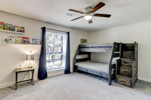 bedroom with ceiling fan, light colored carpet, and a textured ceiling