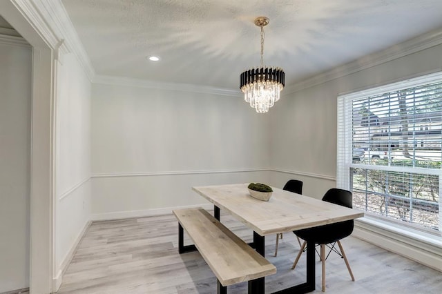 dining room with crown molding, a healthy amount of sunlight, an inviting chandelier, and light wood-type flooring