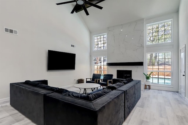 living room featuring a high end fireplace, a healthy amount of sunlight, and high vaulted ceiling