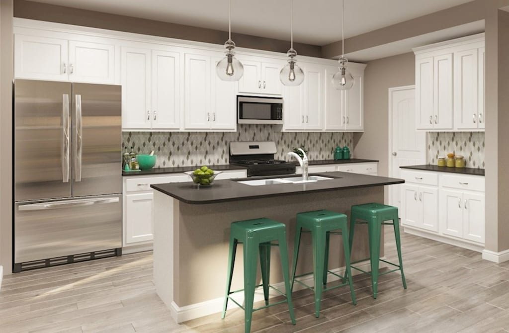 kitchen with sink, a breakfast bar area, white cabinets, stainless steel appliances, and a center island with sink