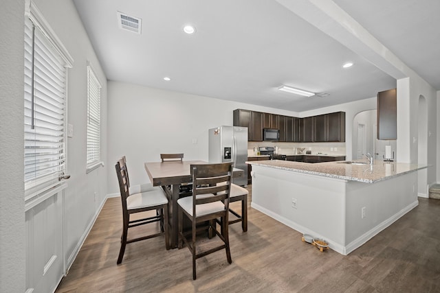 kitchen with dark brown cabinetry, sink, wood-type flooring, and stainless steel appliances