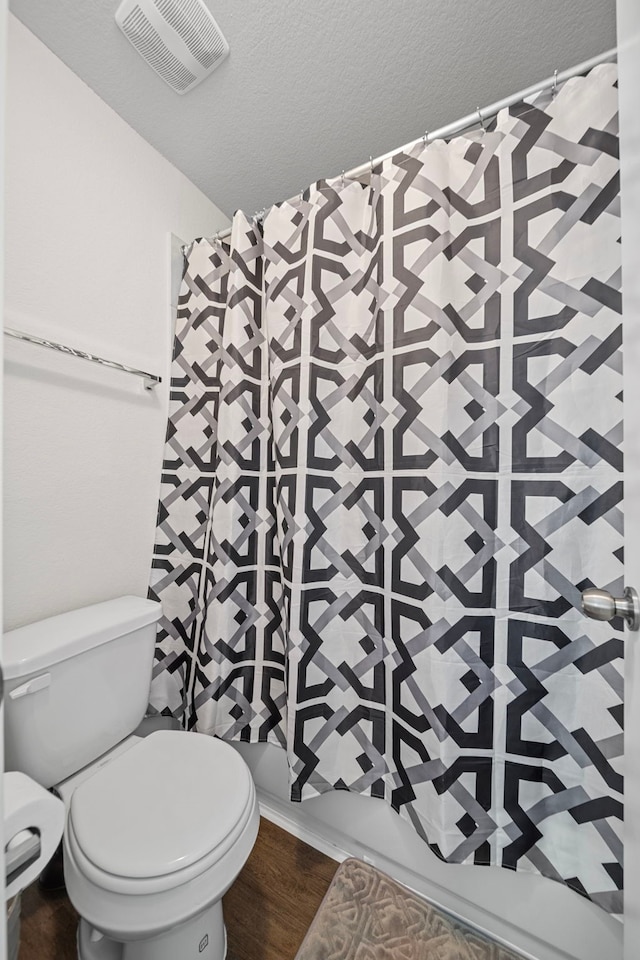 bathroom with hardwood / wood-style flooring, a textured ceiling, toilet, and a shower with shower curtain