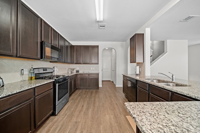 kitchen with dark brown cabinets, sink, light stone counters, and black appliances