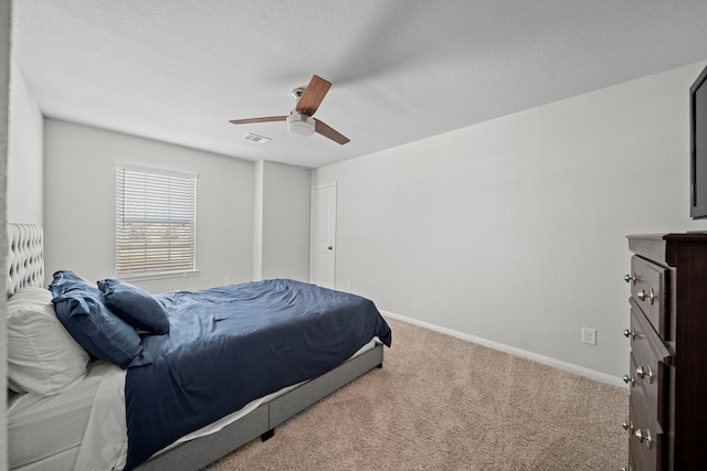 carpeted bedroom featuring ceiling fan and a textured ceiling