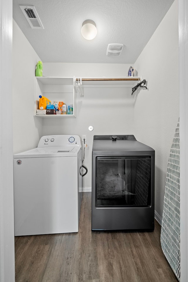 laundry area featuring dark hardwood / wood-style floors, washer and clothes dryer, and a textured ceiling