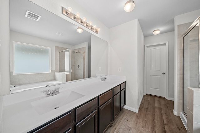 bathroom featuring wood-type flooring, shower with separate bathtub, and vanity