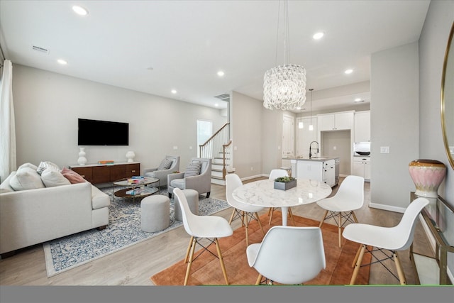 dining space with a chandelier, sink, and light wood-type flooring