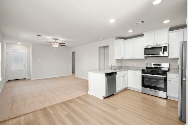 kitchen with sink, stainless steel appliances, white cabinets, and light stone countertops