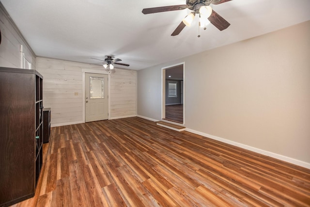 unfurnished living room with wooden walls and dark hardwood / wood-style flooring