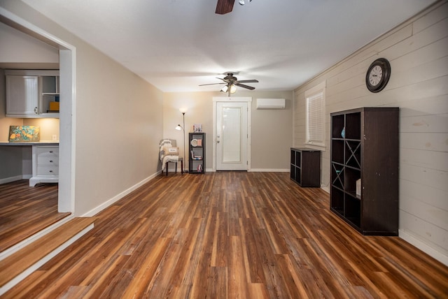 unfurnished living room featuring ceiling fan, built in desk, dark hardwood / wood-style floors, and a wall mounted AC