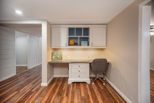 unfurnished office featuring dark hardwood / wood-style floors and built in desk