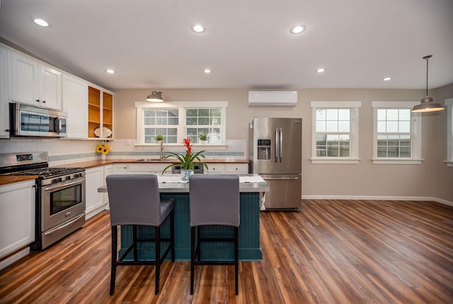 kitchen featuring pendant lighting, sink, white cabinetry, stainless steel appliances, and a wall mounted AC