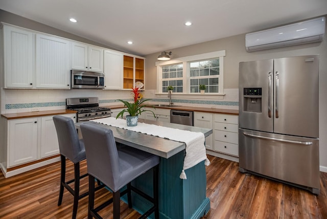 kitchen featuring stainless steel appliances, white cabinetry, dark hardwood / wood-style floors, and a wall mounted air conditioner