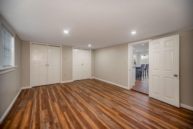 unfurnished bedroom with dark hardwood / wood-style floors and two closets