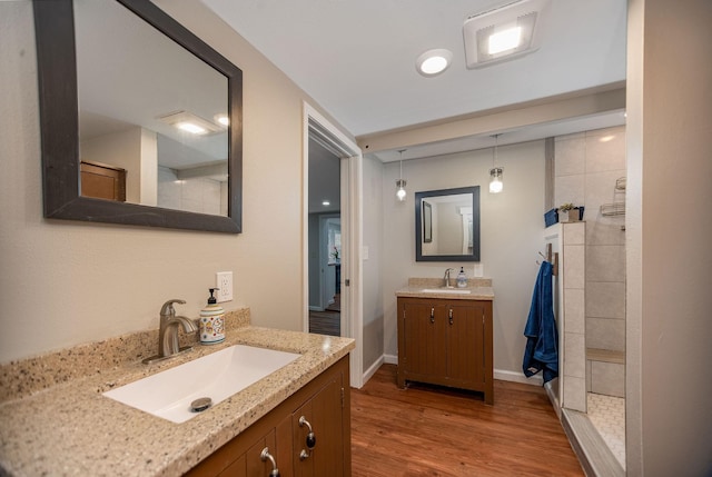 bathroom featuring wood-type flooring, tiled shower, and vanity