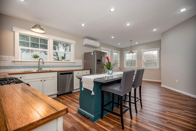 kitchen featuring sink, white cabinetry, stainless steel appliances, a center island, and a wall mounted air conditioner