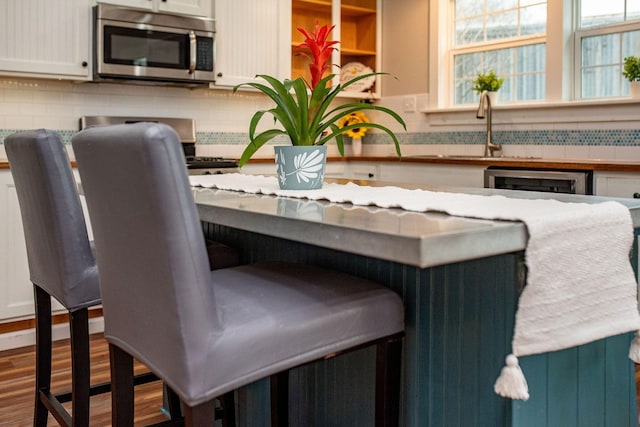 details featuring sink, hardwood / wood-style floors, decorative backsplash, and white cabinets