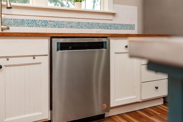 room details featuring backsplash, hardwood / wood-style floors, white cabinets, and dishwasher