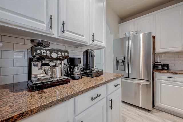 kitchen with decorative backsplash, white cabinets, dark stone counters, and stainless steel fridge with ice dispenser