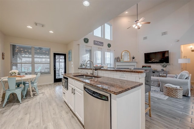 kitchen with sink, appliances with stainless steel finishes, white cabinets, a center island with sink, and light wood-type flooring