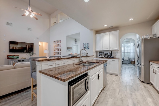 kitchen featuring sink, white cabinetry, a center island with sink, stainless steel appliances, and a kitchen bar