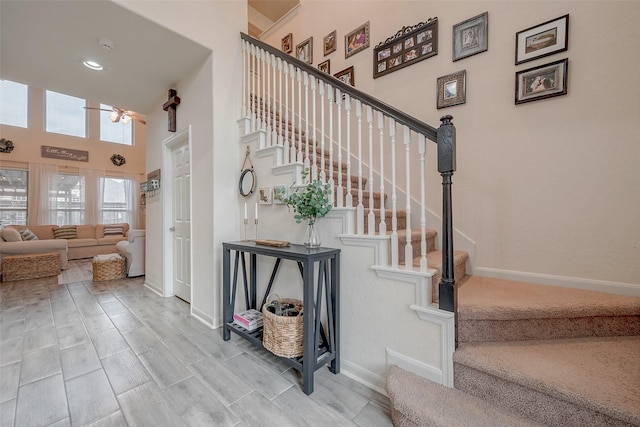 staircase featuring baseboards and a towering ceiling