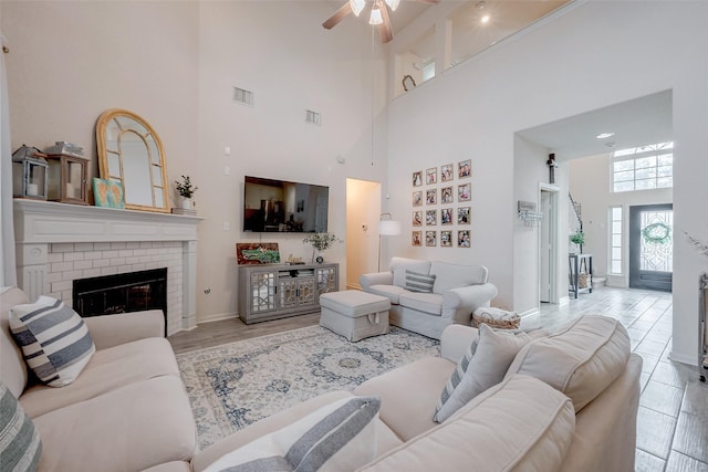 living room with a brick fireplace, ceiling fan, and light hardwood / wood-style floors