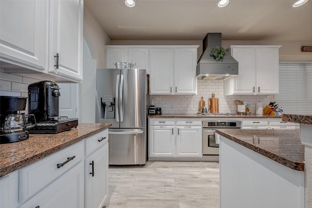 kitchen featuring white cabinetry, dark stone countertops, custom range hood, stainless steel appliances, and backsplash