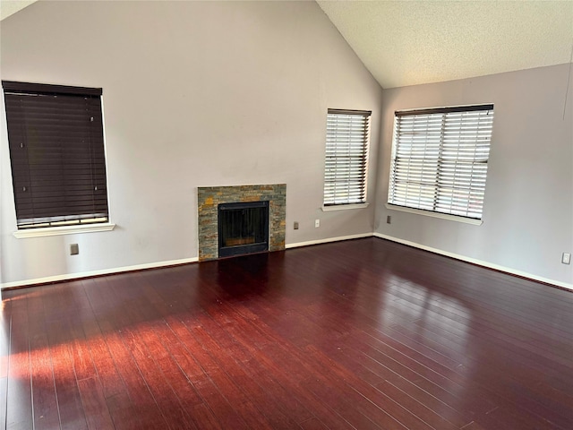 unfurnished living room with wood-type flooring, a fireplace, vaulted ceiling, and a textured ceiling